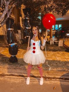 a woman dressed as a clown holding a red balloon