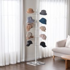 a hat rack with hats on it in front of a white couch and window,