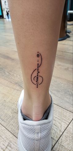 a woman's foot with a musical note tattoo on the side of her leg