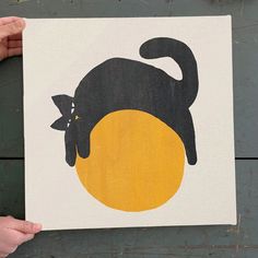 a black cat laying on top of an orange circle metal print with yellow and white background