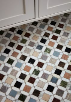 a bathroom with white cabinets and multicolored tiles on the floor