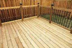 a wooden deck with metal railings next to a fence