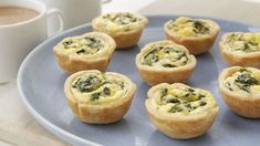 small quiches with spinach and cheese on a blue plate next to a cup of coffee