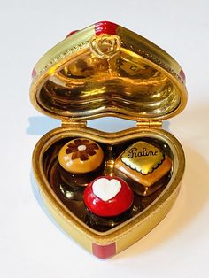 an open heart shaped box filled with assorted chocolates on a white table top