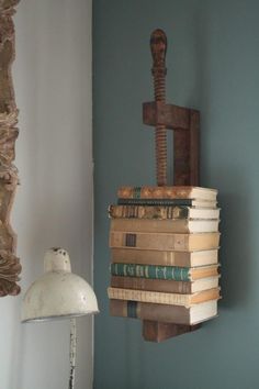 a stack of books sitting on top of a wooden table next to a light fixture