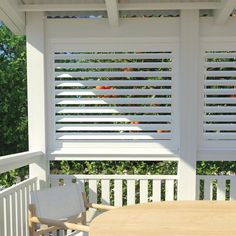 a wooden table sitting on top of a white porch next to a pergolated roof