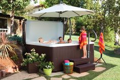 a woman and two children are in the hot tub with an umbrella over their heads