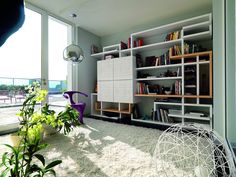 a living room filled with lots of furniture and bookshelves next to a large window