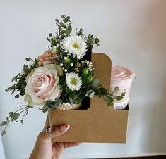 a person holding a box with flowers in it