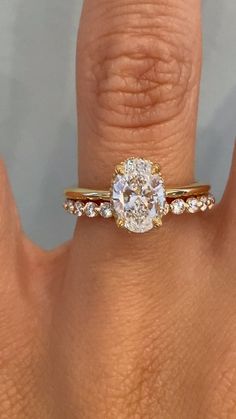 a woman's hand with a diamond ring on top of her finger and an engagement band