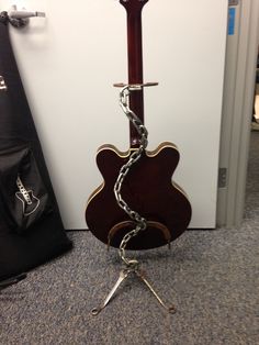 an acoustic guitar chained to a stand on the floor