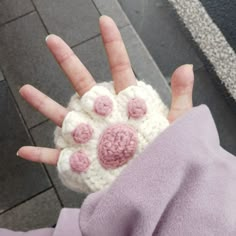 someone is holding their hand up with some crocheted flowers on it's palm