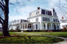 a large white house sitting on top of a lush green field next to a tree