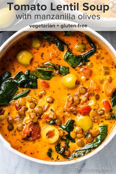 two bowls of soup with olives, spinach and other vegetables on the side