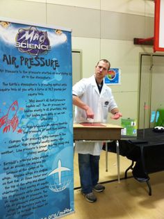 a man in white lab coat standing next to an air pressure sign with writing on it