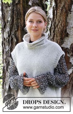 a woman standing in front of a tree with her arms crossed and looking at the camera