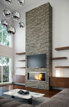 a living room with a large stone fireplace in the center and lots of glass balls hanging from the ceiling