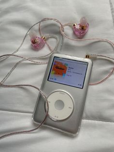 an ipod sitting on top of a bed next to headphones and cords in front of it