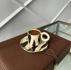 a coffee cup sitting on top of a brown suitcase