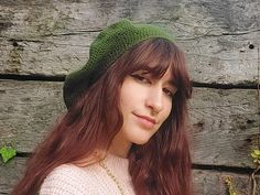 a woman with long red hair wearing a green knitted hat and posing for the camera