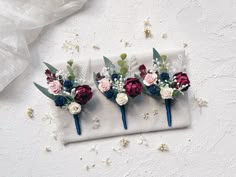 three boutonnieres with red, white and blue flowers sit on a napkin