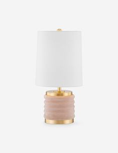 a pink and gold table lamp with a white shade on the top, against a white background