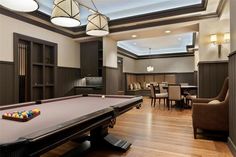 a pool table in the middle of a room with chairs around it and a skylight overhead