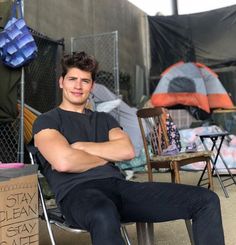 a man sitting in a chair with his arms crossed next to a cardboard box on the ground