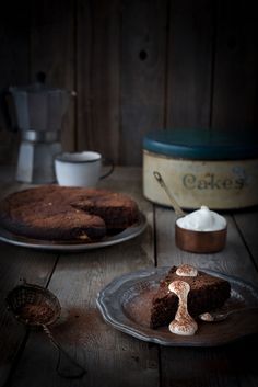 two cakes sitting on top of a wooden table next to a cup and saucer