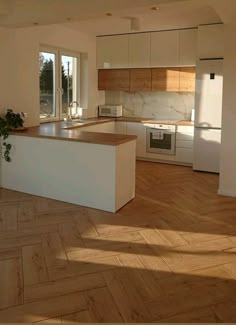 an empty kitchen with wooden floors and white cabinets in the background, looking out to outside