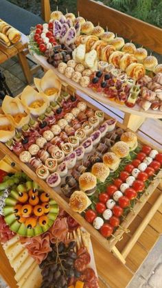 an assortment of food is displayed on a wooden table with plates and trays filled with different types of foods