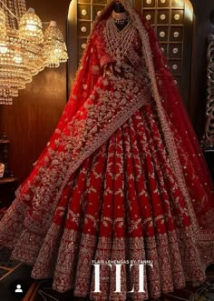 a red bridal gown is displayed in front of a chandelier