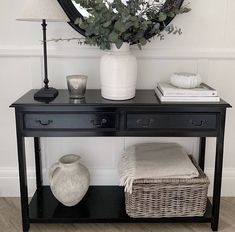 a black table with a mirror and vase on it