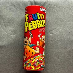 a can of fruity pebbles sitting on top of a gray couch next to a pillow