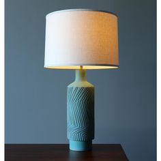 a lamp that is on top of a wooden table next to a blue and white vase