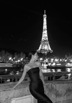 black and white photograph of woman in front of the eiffel tower at night