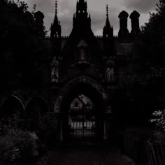 an old building with a gate in front of it on a cloudy day at night