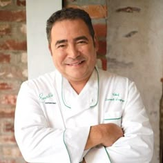 a black and white photo of a man in a chef's coat with his arms crossed