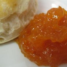 an orange jelly is sitting on a white plate next to a pastry that has been cut in half