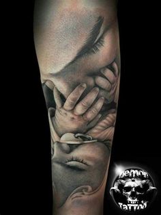 a man's arm with a black and grey tattoo on it, holding his hands to his face