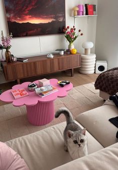 a cat is standing in the middle of a living room with a pink coffee table