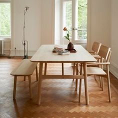 a wooden table with four chairs and a bench in front of it on a hard wood floor