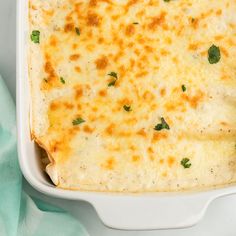 a casserole dish with cheese and parsley in it on a green napkin