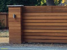 a brown wooden fence with a black cat sitting on top of it