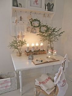 a white table topped with lots of candles next to a shelf filled with books and plants