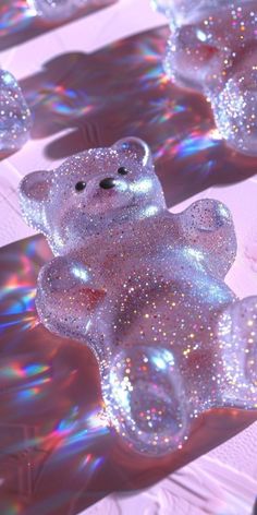 a shiny teddy bear sitting on top of a table covered in glittery materials