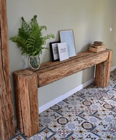 a wooden bench sitting next to a potted plant on top of a tiled floor