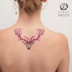 the back of a woman's neck with pink flowers and a deer head on it