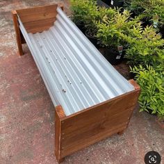 a wooden bench with metal slats on top of it next to potted plants