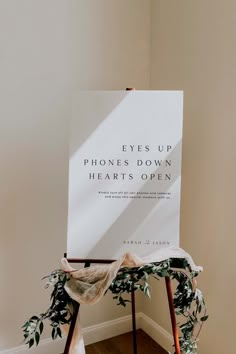 a sign that says eyes up phones down hearts open on top of a wooden easel